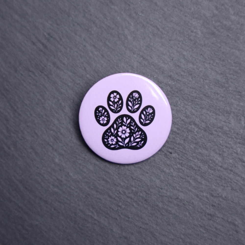Floral Paw Purple Button. These buttons are made with photo paper, metal round, and metal backing. These buttons are vibrant and fun to use on bags or vests.