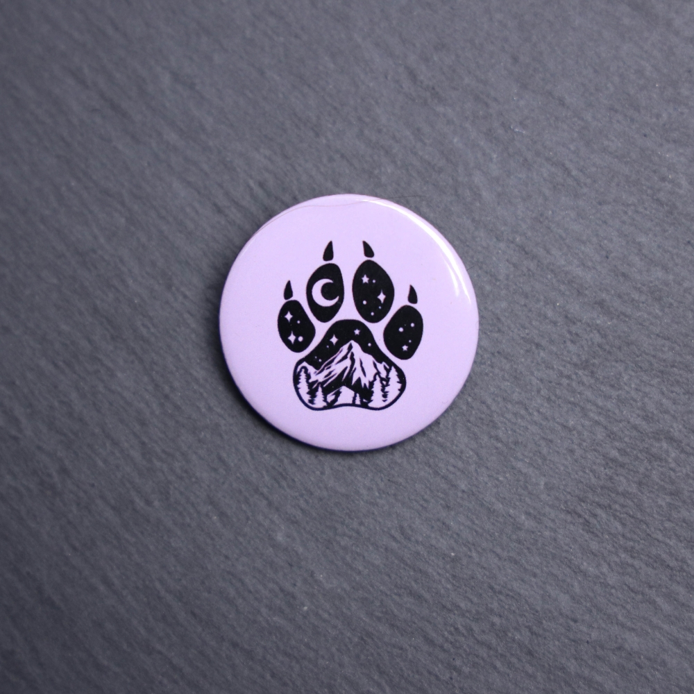 Forest Paw Purple Button. These buttons are made with photo paper, metal round, and metal backing. These buttons are vibrant and fun to use on bags or vests.