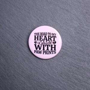The Road To My Heart Is Paved With Paw Prints Button. These buttons are made with photo paper, metal round, and metal backing. These buttons are vibrant and fun to use on bags or vests.