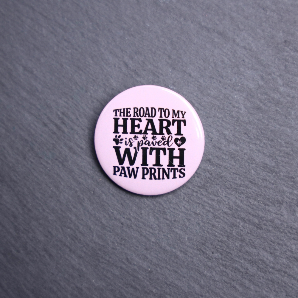 The Road To My Heart Is Paved With Paw Prints Button. These buttons are made with photo paper, metal round, and metal backing. These buttons are vibrant and fun to use on bags or vests.